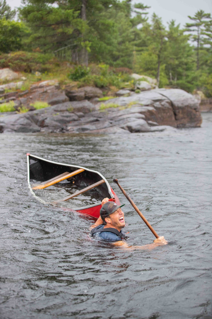 A man in the water with a capsized canoe.