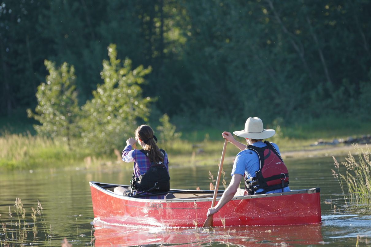 Tandem canoe team paddling through marsh.