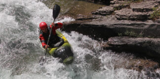 person whitewater kayaking down a raging creek