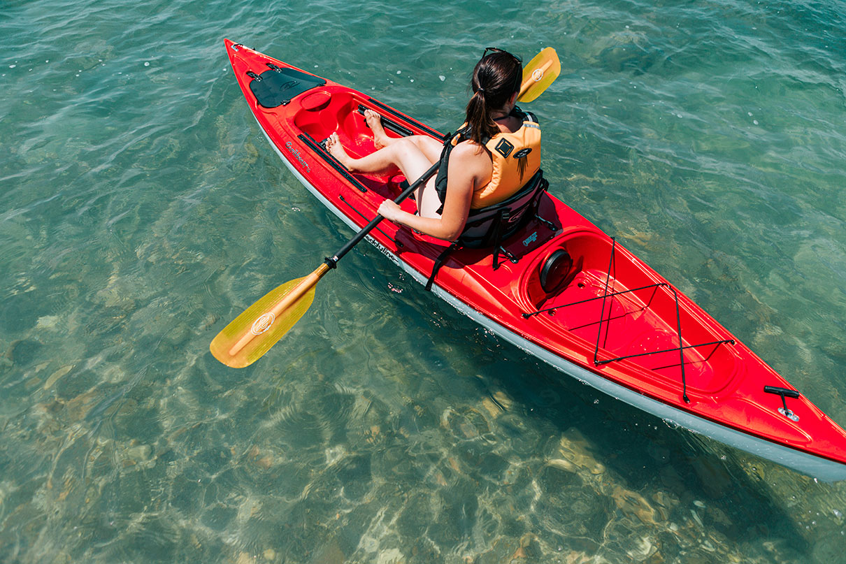 woman paddles a red recreational sit-on-top kayak