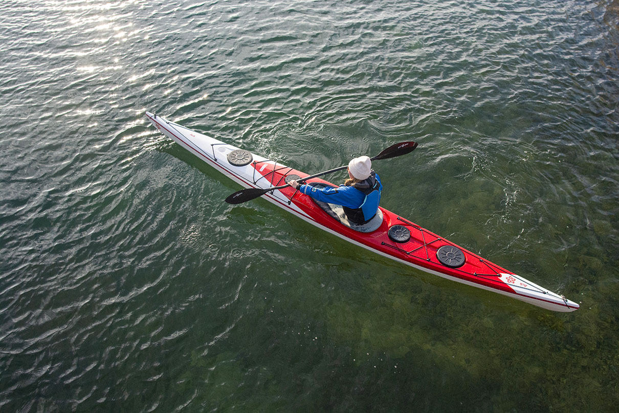 person in toque and drysuit paddleing a sit-inside touring kayak