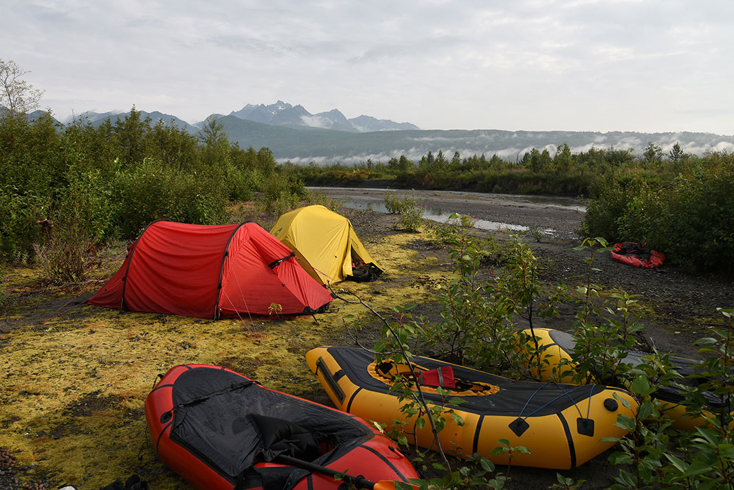 two tents and three packrafts at a backcountry camping site