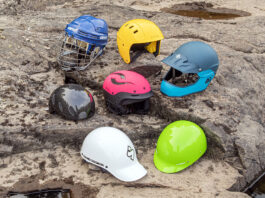 a selection of whitewater helmets are arranged on a river rock