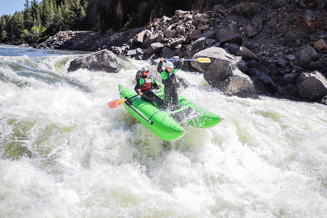 two men race a whitewater raft down a class V river