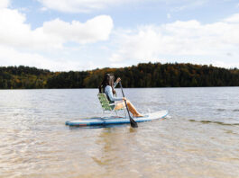 a woman demonstrates sit down paddleboarding using a lawn chair