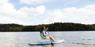 a woman demonstrates sit down paddleboarding using a lawn chair
