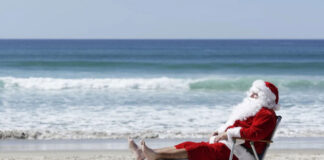 santa relaxing with his feet up at the beach