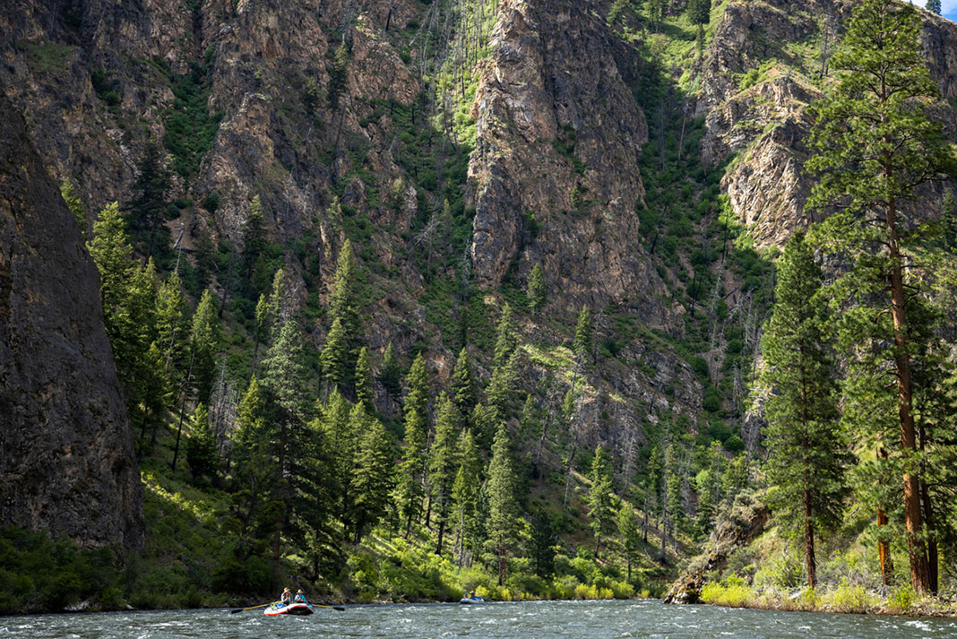 a raft floats in front of steep rock face along the Salmon River
