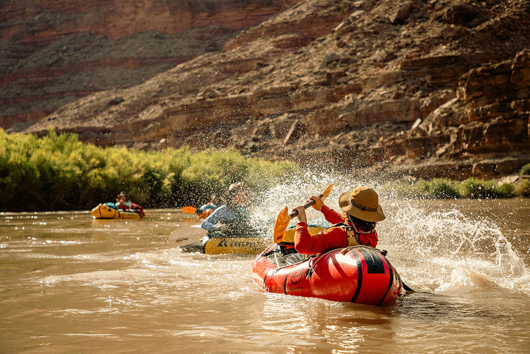 three packrafters playfully splash each other on the San Juan River