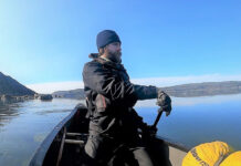 man paddles a canoe on a solo expedition in cold weather