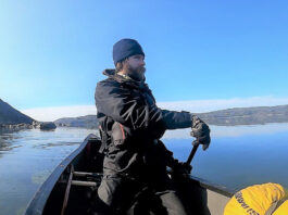 man paddles a canoe on a solo expedition in cold weather