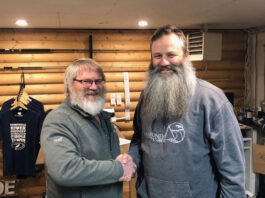 the previous and new owners of Churchill River Canoe Outfitters shake hands