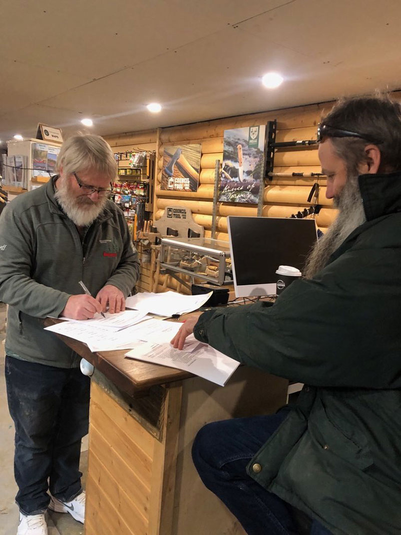 two men sign documents at Churchill River Canoe Outfitters