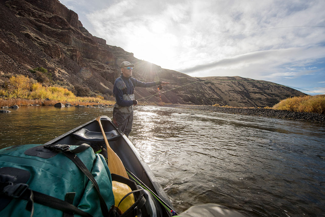 angler fishes near his canoe while tripping down the John Day River