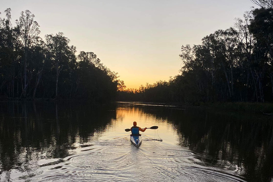 Kayaker paddles down the Murray River in silhouette