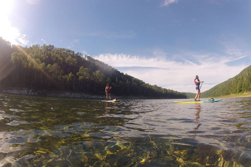 Two people paddleboard on a sunny lake in Quebec