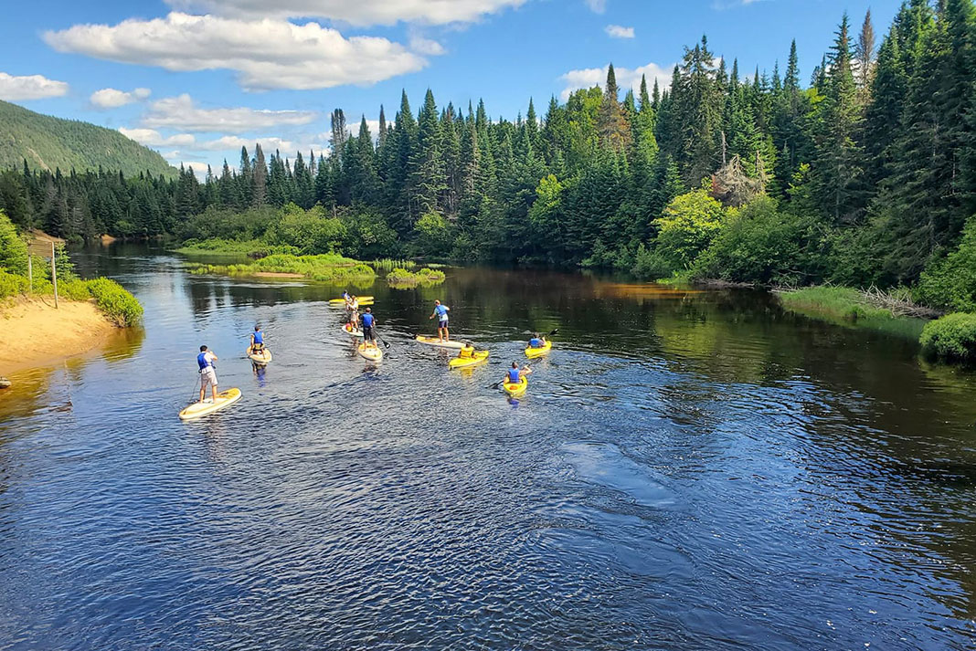 a group of paddleboarders on a scenic river in Quebec