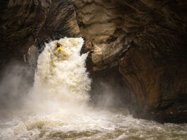 a whitewater kayaker drops off a rushing waterfall in a cavern