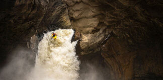 a whitewater kayaker drops off a rushing waterfall in a cavern