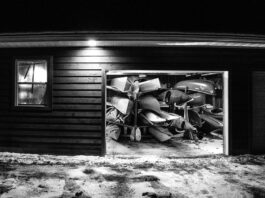 black and white photo looking into a garage full of paddling gear at night with garage door open