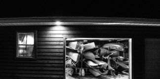 black and white photo looking into a garage full of paddling gear at night with garage door open