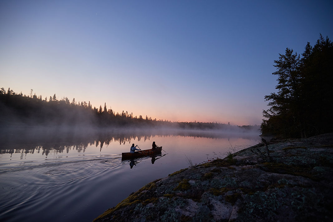 man and woman paddling on a misty morning lake in Minnesota's Boundary Waters Canoe Area