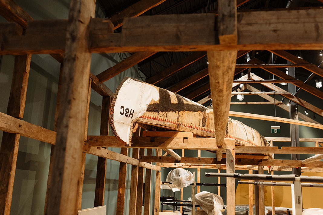 An HBC canoe rests in the rafters next to salvaged building beams