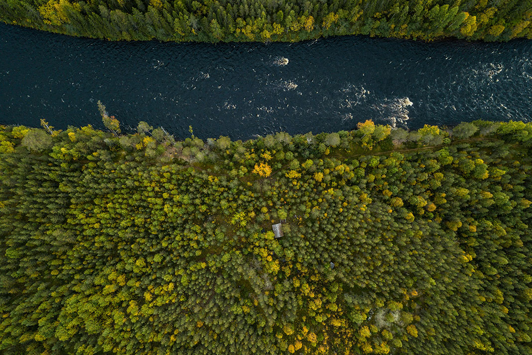 overhead view of a rushing river surrounded by dense forest in Sweden