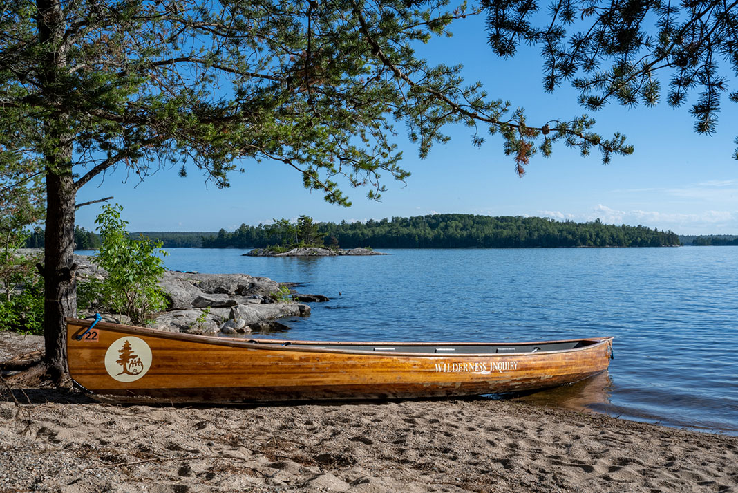 a wooden canoe sits beached on a sandy shoreline