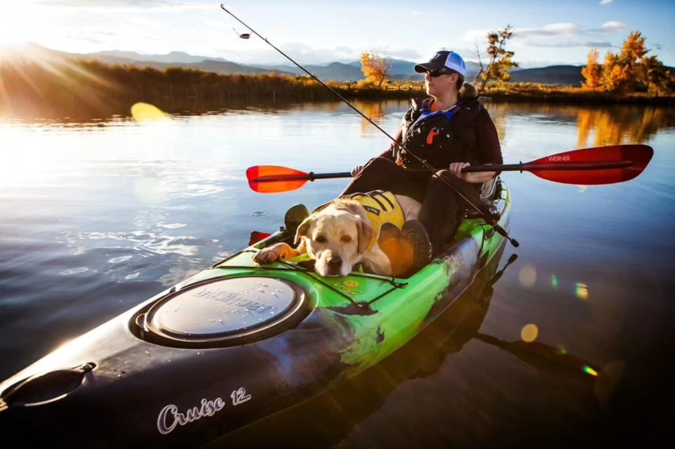 Kayak angler with dog in boat.