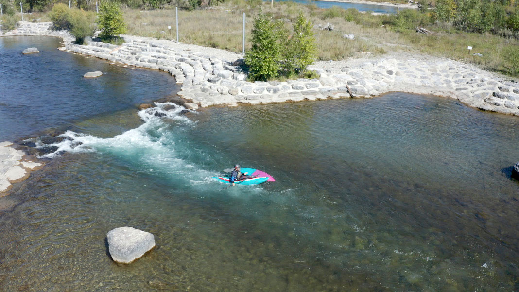 paddling out of the eddy to reach the kayak in the rapid