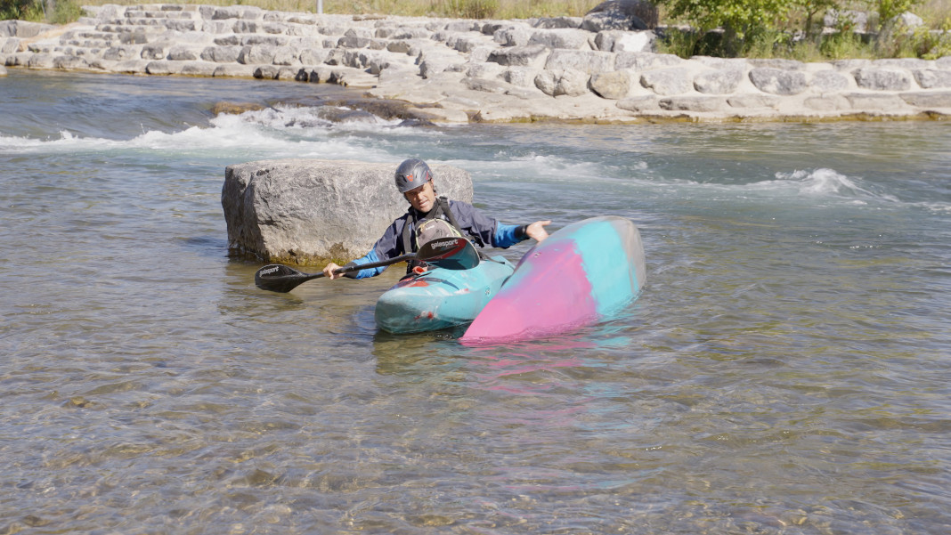 man demonstrates how to perform a kayak rescue in whitewater