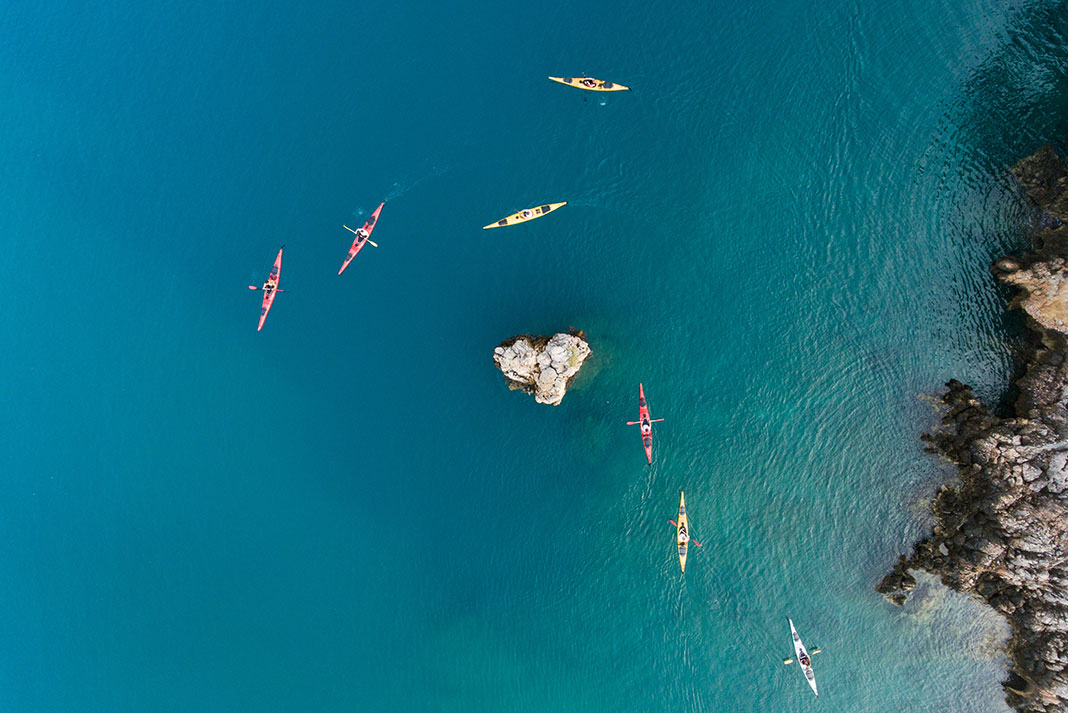 overhead view of a group of kayakers paddling in the turquoise waters of Greece
