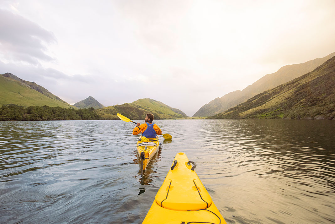 two kayakers paddle in New Zealand