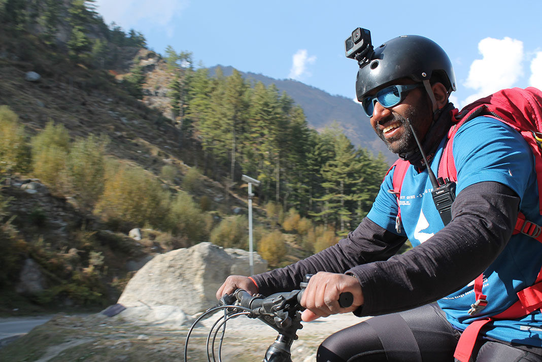 Rency Thomas rides his bike past river with GoPro on helmet