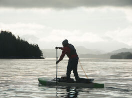 man silhouetted as he paddleboards across the dangerous Hecate Strait in British Columbia