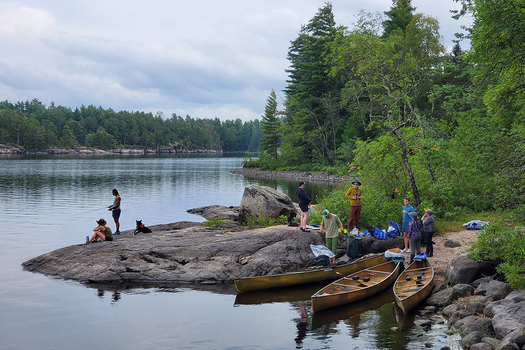 a group of canoe trippers gather on the rocky shore of a lake in Minnesota