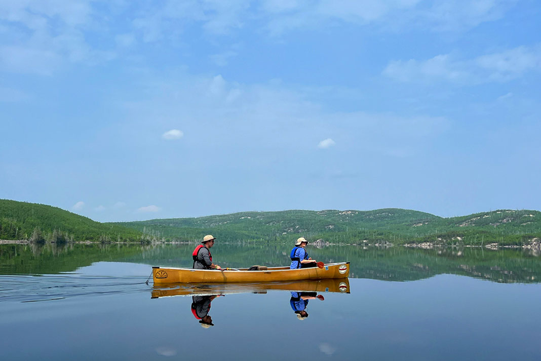 Two people paddle a canoe along the Boundary Waters Gunflint Trail