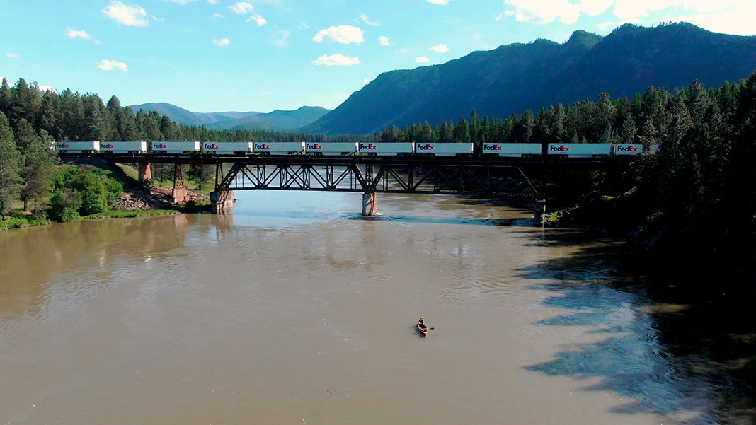 canoeists prepare to paddle under a rail bridge as part of the Columbia River Canoe Project