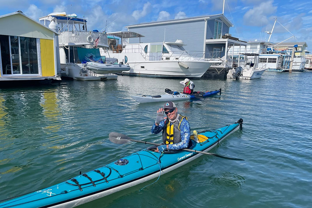 two people kayak past houseboats while on the Florida Circumnavigational Saltwater Paddling Trail