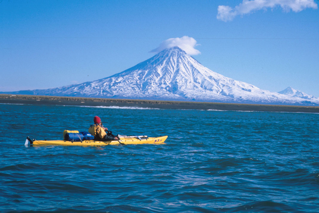 man sits in kayak in front of Mount Fuji