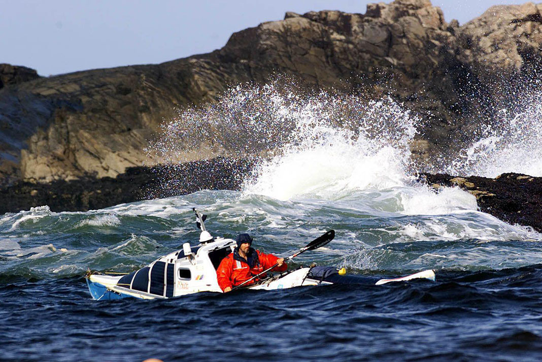 Peter Bray paddles his custom expedition kayak among the surf