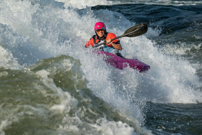 a person whitewater kayaking in a Jackson kayak with a Werner paddle