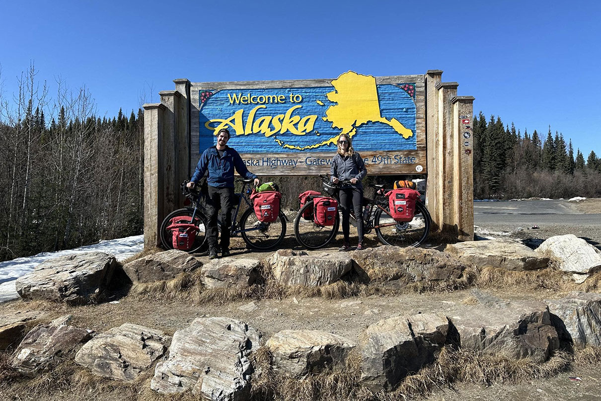 two members of the Expedition AKOR team pose in front of an Alaska sign