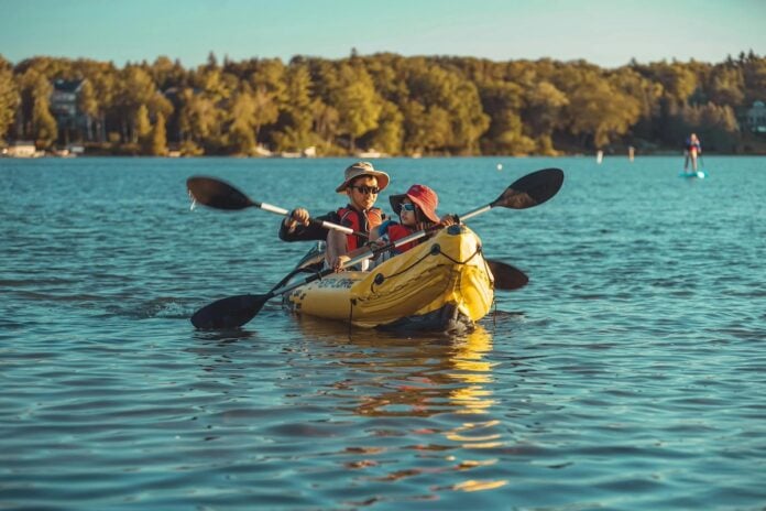 an adult and a child paddle an inflatable kayak together