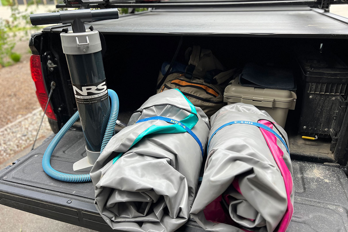 AIRE Spud and Tater sit packed up on a truck tailgate beside an NRS hand pump