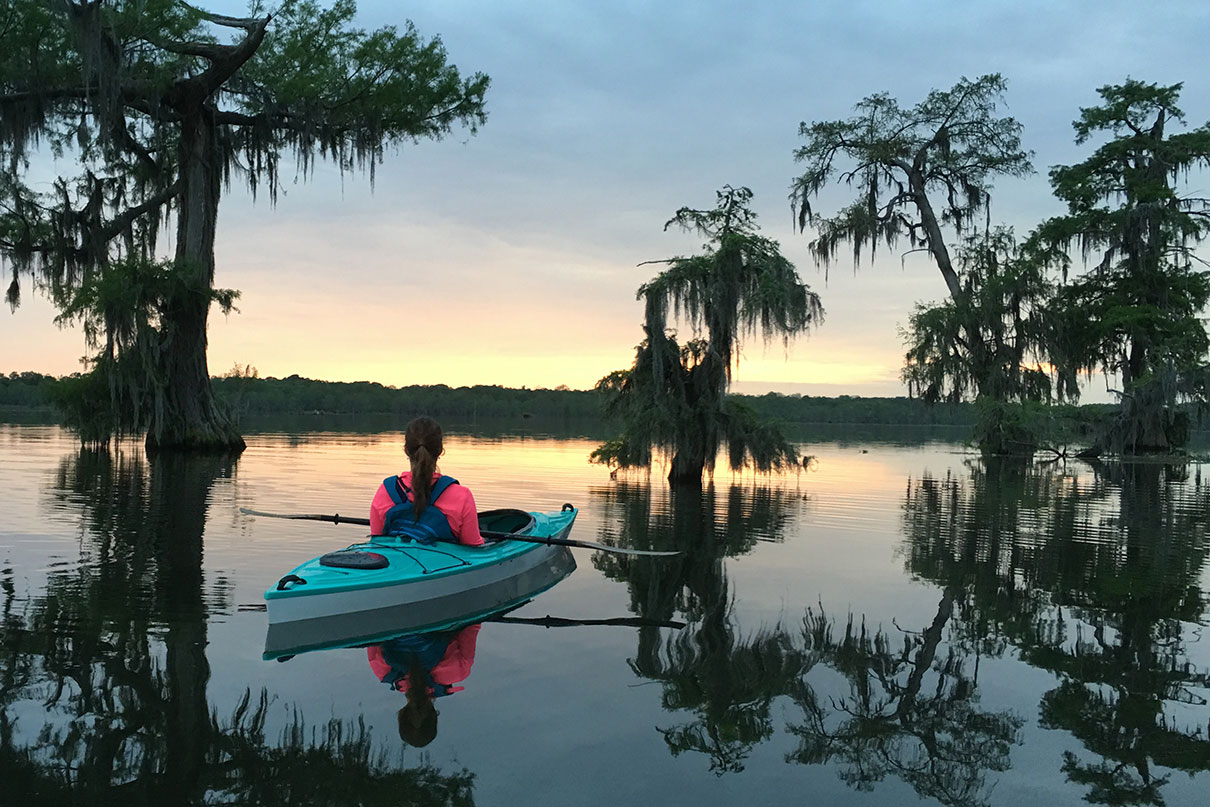 woman sits in kayak at sunset