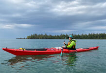 woman poses while sea kayaking in rainy weather