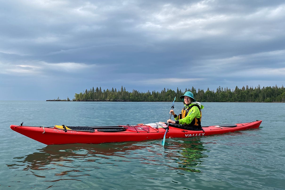 woman poses while sea kayaking in rainy weather