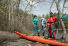 man and women put on drysuits while preparing for a kayaking excursion